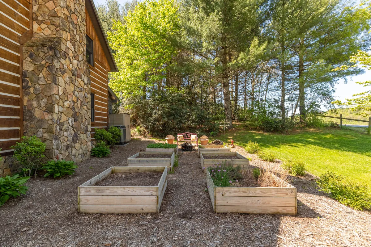 Seen here is an outdoor seating area adjacent to a stone wall, with raised garden beds and comfortable chairs inviting guests to relax. The setting is peaceful and perfect for social gatherings or quiet reflection after visiting local attractions.