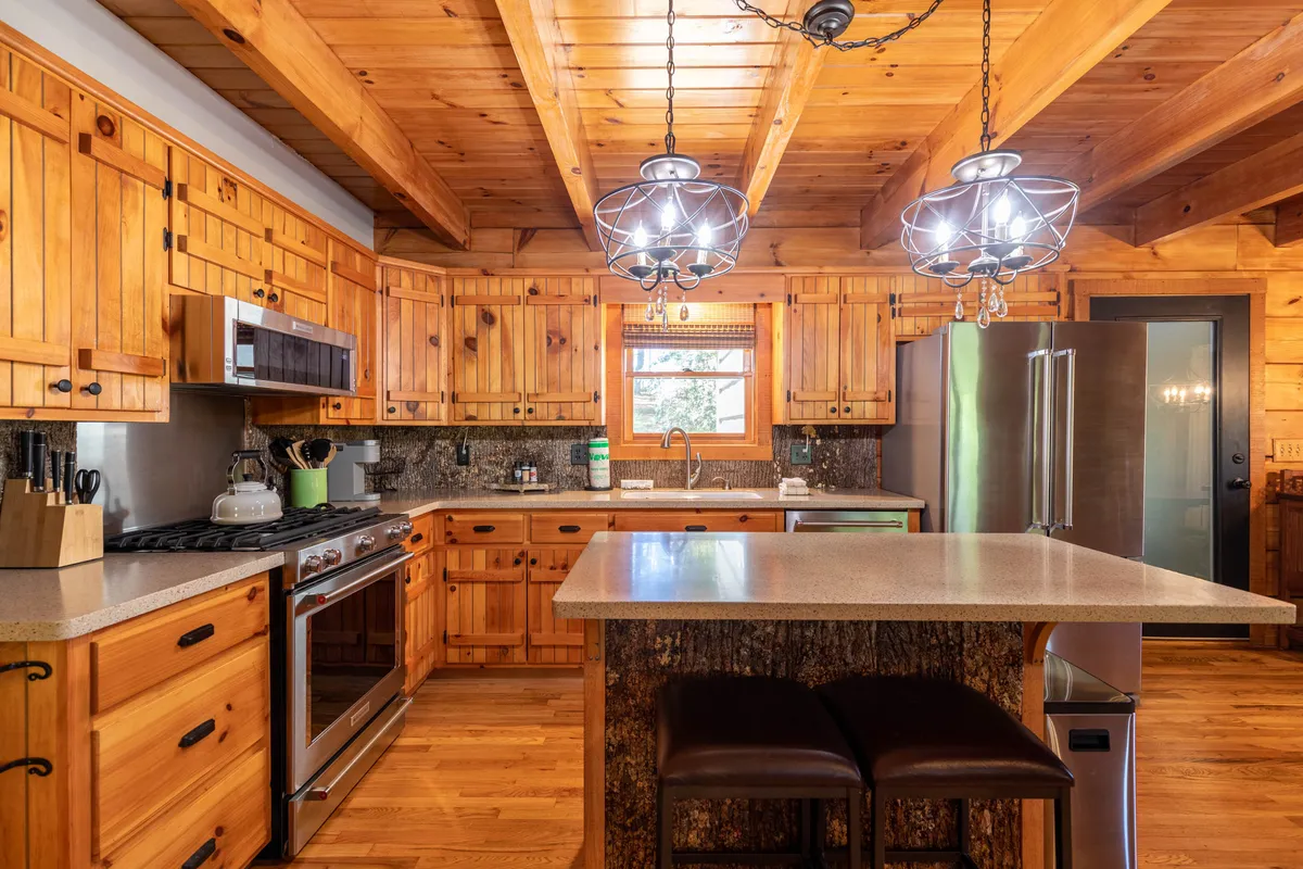A bright, modern kitchen with wooden cabinets, a central island with bar stools, and windows letting in natural light. The space is designed for family meals, entertaining guests, and casual moments, offering plenty of room for movement—perfect for families with pets who need space to move around comfortably and safely.