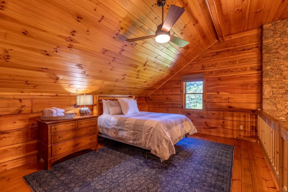 A serene bedroom scene with a comfortable bed, nightstand, window letting in sunlight, and a textured rug. The setting is both inviting and peaceful, suggesting a tranquil night's sleep and refreshed mornings.