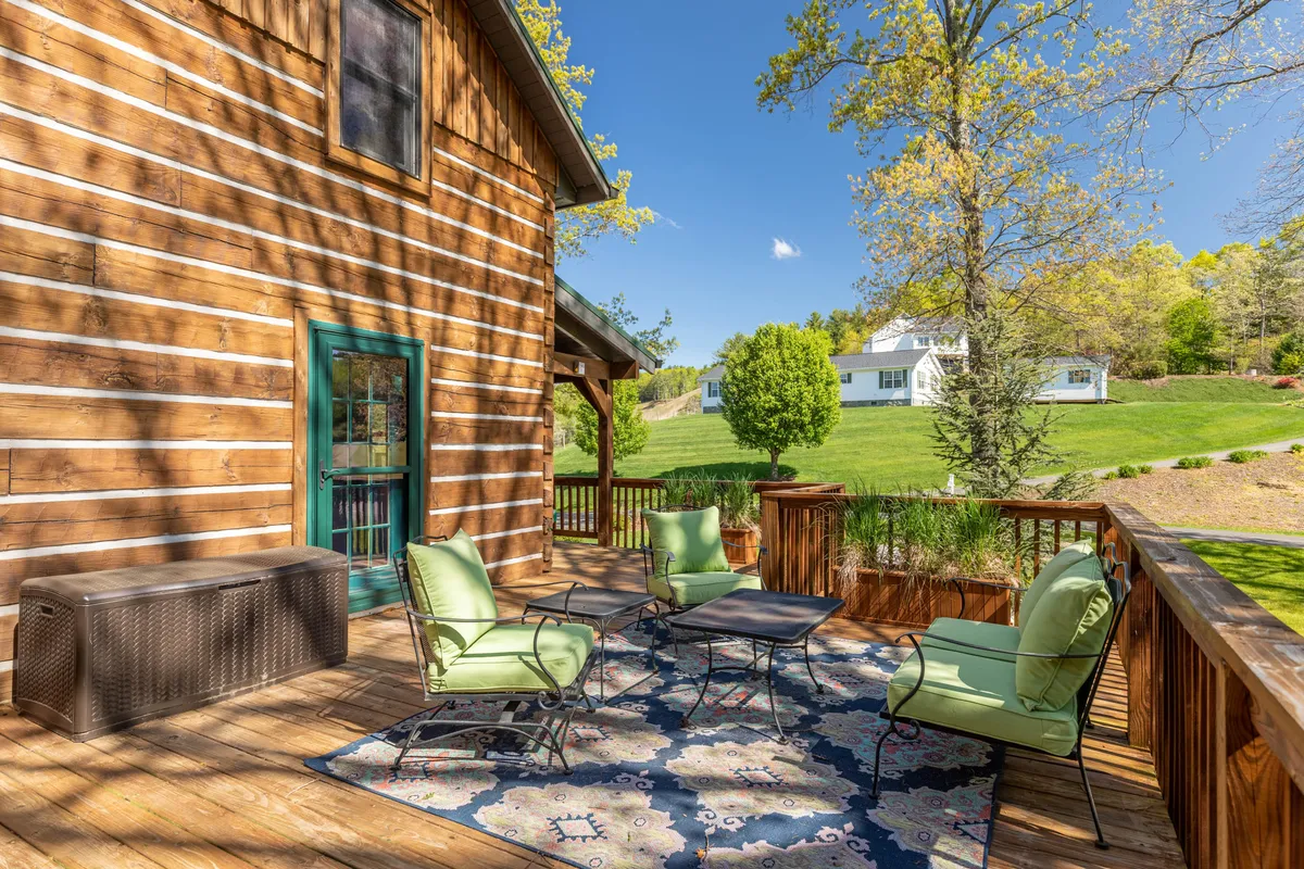 A peaceful corner of the deck with green chairs, a decorative rug, and surrounding trees. The scene conveys relaxation, privacy, and immersion in natural beauty—perfect for quiet mornings or evenings outdoors.
